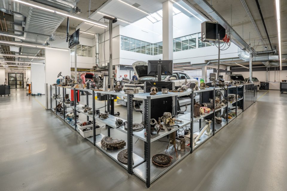 Steel shelves of used engine parts, brake discs and clutch plates in a bright, modern repair shop